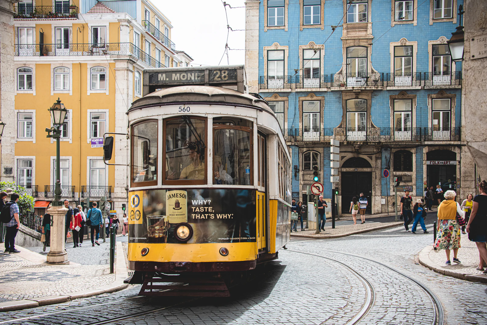 Yellow Tram 28 climbing a steep cobblestone street in Alfama