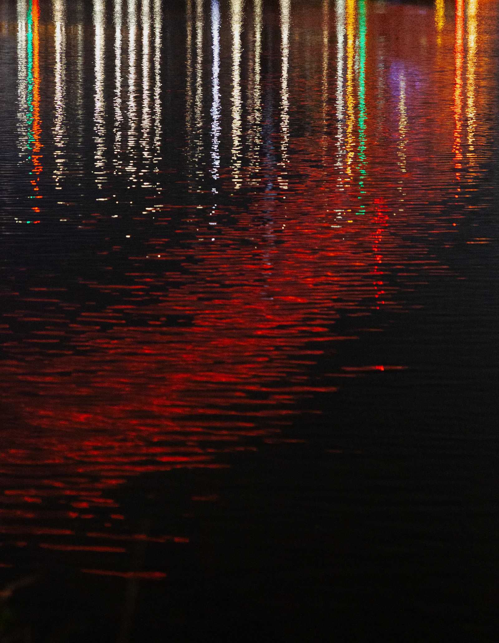 Reflection of neon signs in a puddle on pink-painted pavement