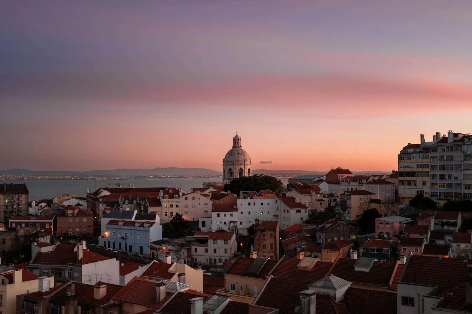 Tagus river at golden hour with Lisbon skyline silhouetted against orange sky
