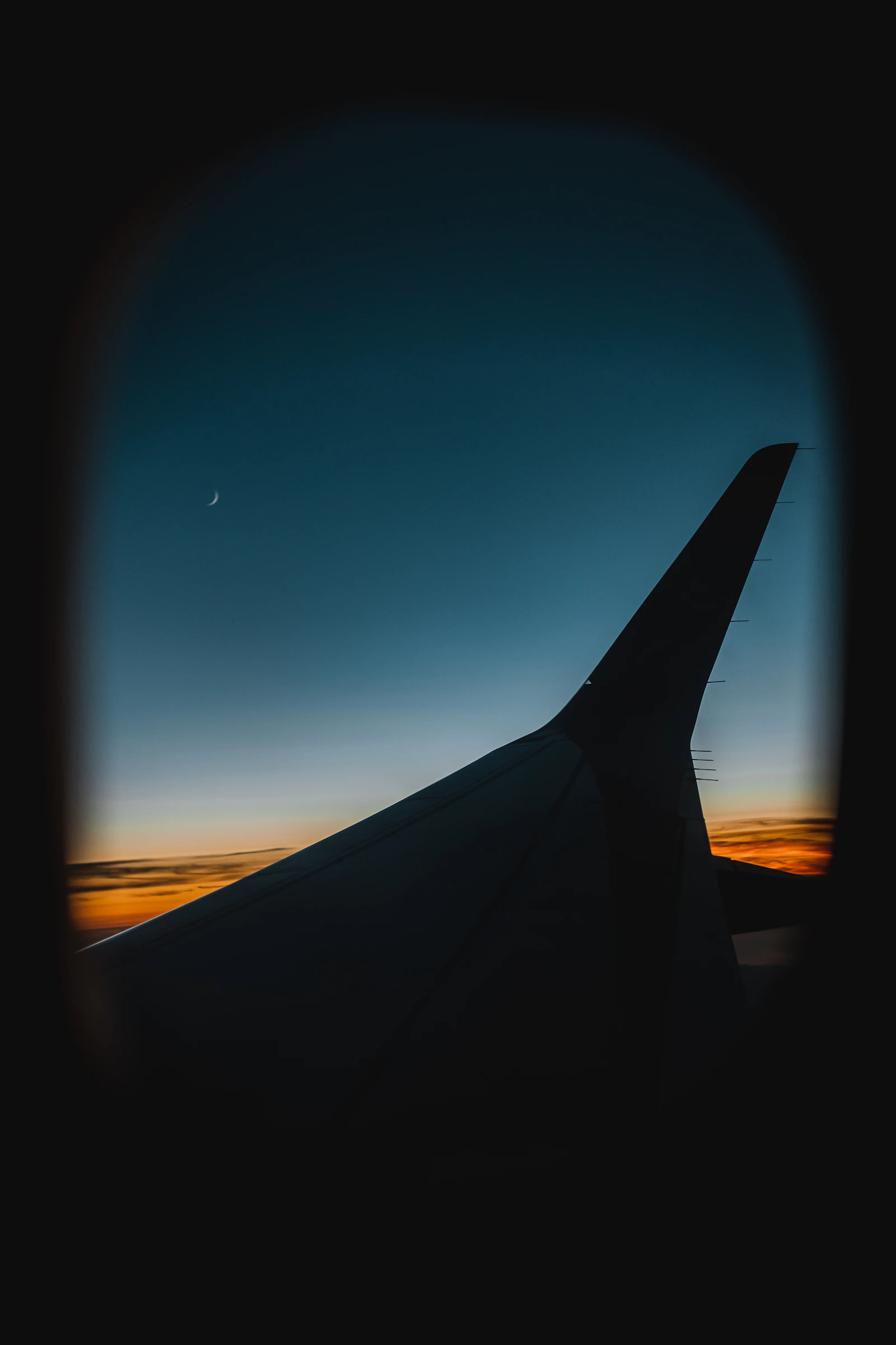 Window seat view of an airplane wing above orange clouds at dusk