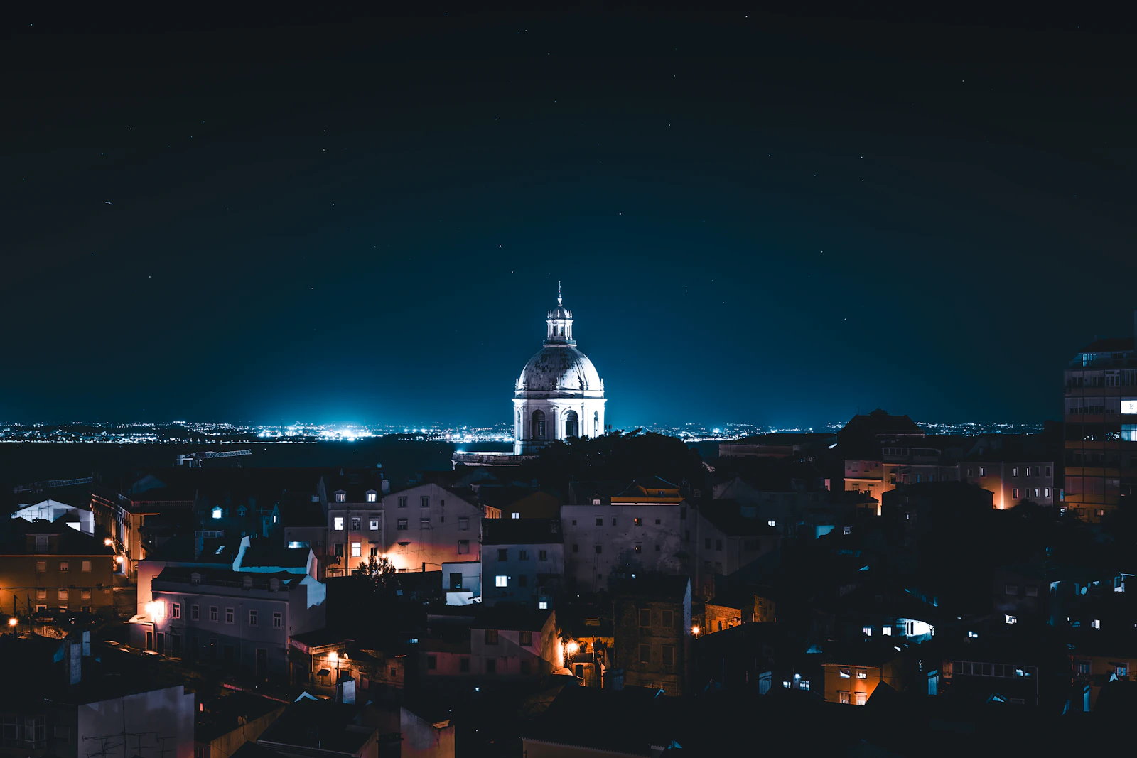 Lisbon old town skyline at night with city lights glowing against the hills
